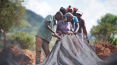 Members of the Itinyi Valley community set up shade netting